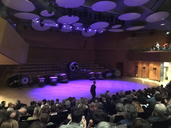 車イス観覧席から撮影した舞台。舞台奥に和太鼓が準備されていて、紫のライトアップで舞台が照らされている。