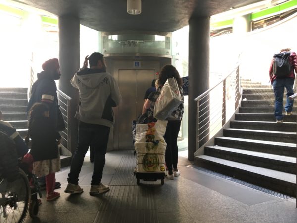 地下鉄からミラノ中央駅へつながるエレベーターの正面を撮影したもの。エレベーターは半透明で、エレベーターを囲むように螺旋階段が設置してある。